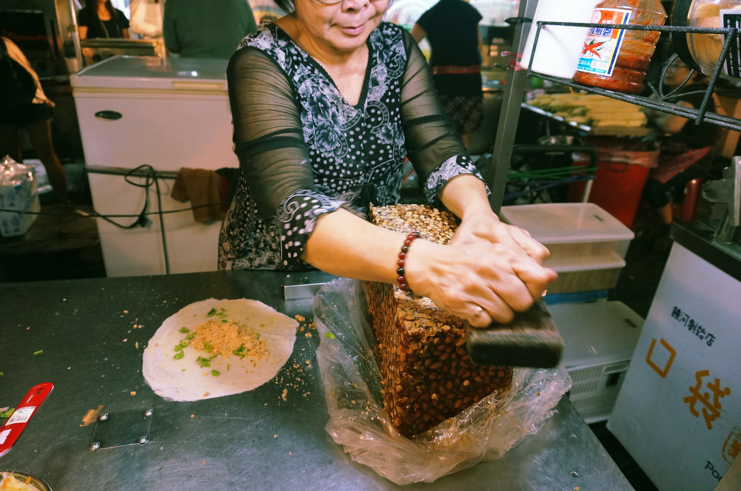 台湾「饒河街観光夜市」にてナッツの塊をかんなで削るおばちゃん